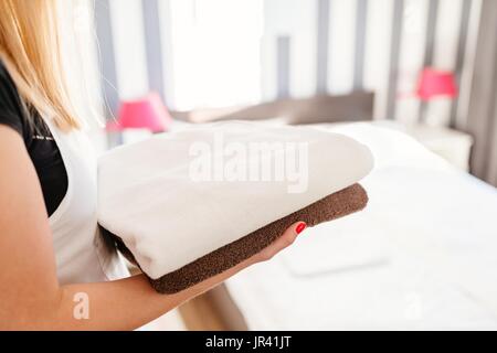 Young hotel maid bringing fresh clean towels to the room. Stock Photo