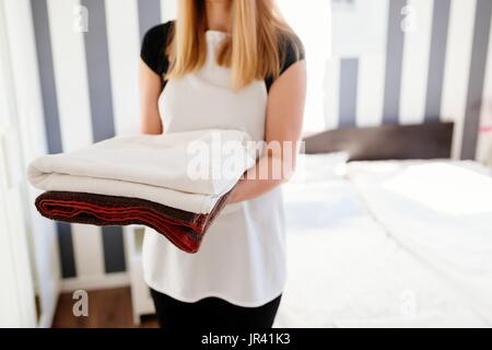 Young hotel maid bringing fresh clean towels to the room. Stock Photo