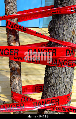 Red danger tape wrapped around a tree. Stock Photo