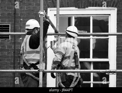 Two workers assembling scaffolding on city building Stock Photo