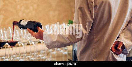 Waiter pours red wine from a bottle Stock Photo