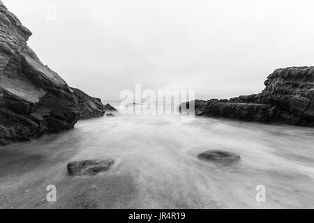 Rocky Malibu beach with motion blur water in Black and White. Stock Photo