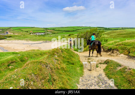 Horse riding on a UK beach on the South West Coast Path at Gunwalloe beach, Lizard Peninsula, Cornwall, UK in summer Stock Photo