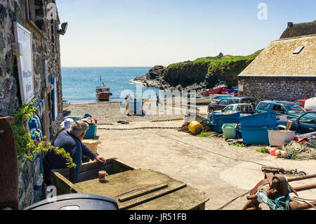 Fishing boats and fishermen at Cadgwith Cove, Lizard Peninsula, Cornwall, UK in summer landing a catch Stock Photo