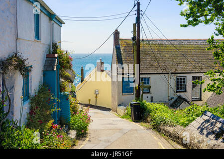 Village UK street in Cadgwith, Cornwall, UK on the Lizard Peninsula in summer with the sea behind Stock Photo
