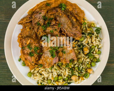 Aromatic Lamb Curry With Vegetable Rice Against a Green Wooden Background Stock Photo