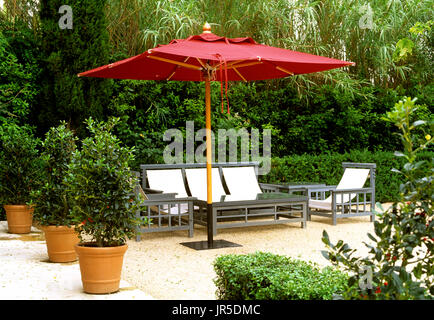 Outdoor umbrella with table and chairs in a courtyard Stock Photo