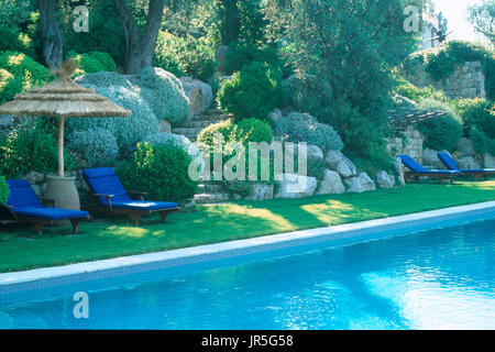 Recliners by swimming pool Stock Photo