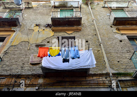 Looking up at washing drying on apartment balcony in a building needing refurbishment Stock Photo