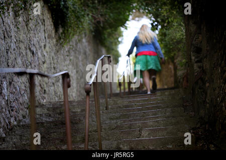 An unidentified young woman walks on away from camera up a set of steep steps. (posed by model) Stock Photo