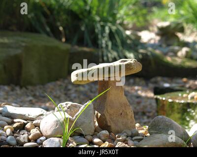 Zen garden rock balancing on another rock, with blades of grass in foreground Stock Photo