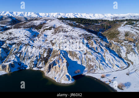 Snow around Blue Lake, St Bathans, and Hawkdun Range, Maniototo, Central Otago, South Island, New Zealand - drone aerial Stock Photo