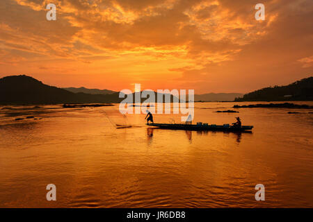 Silhouette of two fishermen in a boat at sunset, Thailand Stock Photo