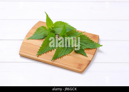 fresh nettle leaves on wooden cutting board Stock Photo
