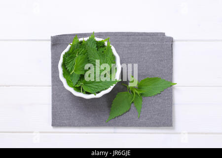 bowl of fresh nettle leaves on grey place mat Stock Photo