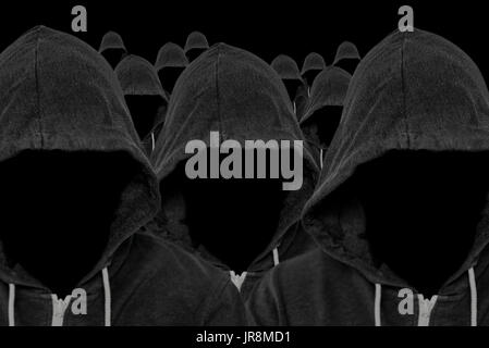 Mass of faceless mysterious and unknown hooded people with unseen faces and a black background Stock Photo