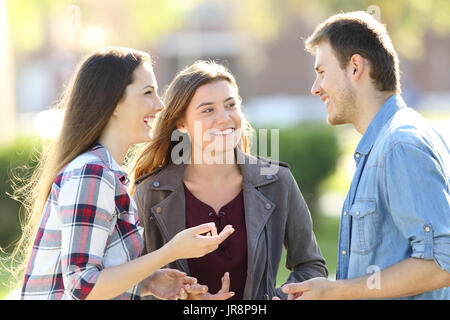 Three happy friends having a conversation and laughing in the street Stock Photo