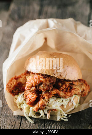 Fried boneless chicken sandwich with coleslaw on wooden surface Stock Photo