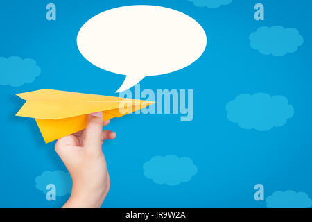 hand holding paper plane with speech bubble on blue background Stock Photo
