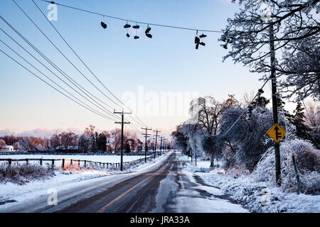 Frozen Shoes on a line are covered in ice from an ice storm. This peaceful country road shows a tranquil winter scene with a bit of personality. Stock Photo