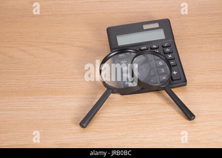 High angle view of calculator with two magnifying glasses lying on wooden table Stock Photo