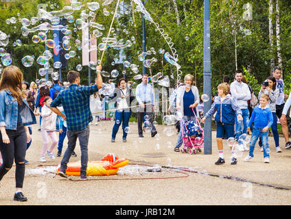 Street entertainer soliciting tips entertaining children by blowing large colourful bubbles, Bankside, Embankment, South Bank, London SE1, UK Stock Photo