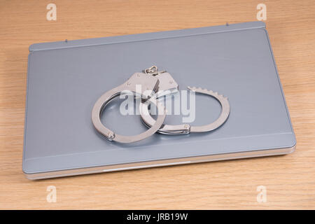 High angle view of open handcuffs lying on laptop Stock Photo