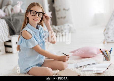 Smart young lady posing for camera while preparing school assignment Stock Photo