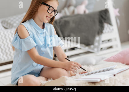 Happy schoolgirl writing in notebook Stock Photo