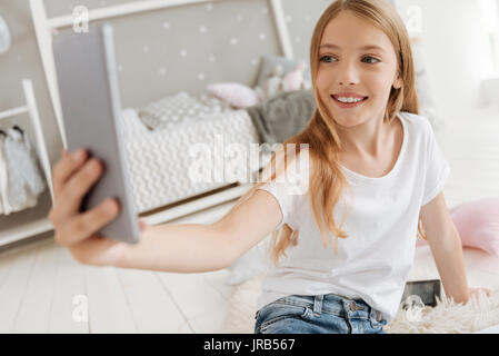 Excited little girl taking selfies in her bedroom Stock Photo