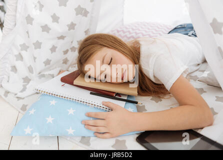 Tired girl sleeping after working hard on home assignment Stock Photo