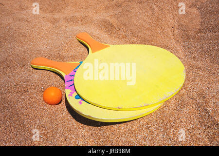 close-up of two rackets and ball on the beach sand Stock Photo