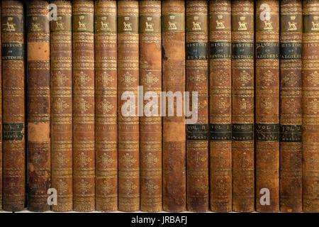 Collection of old antique books in a brown cover on the bookshelf Stock Photo