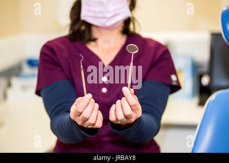 Dental nurse demonstrating dental examination instruments set - a mouth mirror and periodontal probe Stock Photo