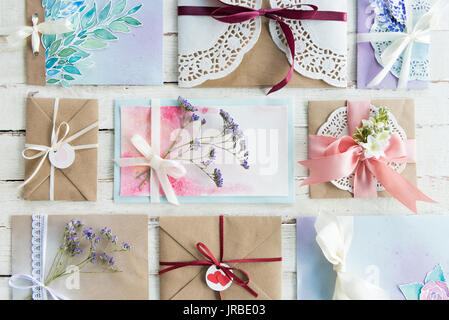 top view of collection of envelopes or invitations on white wooden tabletop, wedding invitation card design concept Stock Photo
