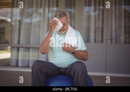 Senior man wiping sweat off his face with towel after exercising Stock Photo