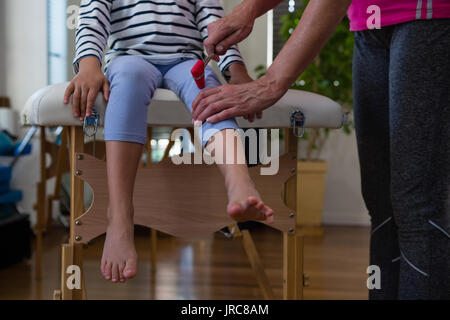 Doctor examining reflexes of patient knee in clinic Stock Photo
