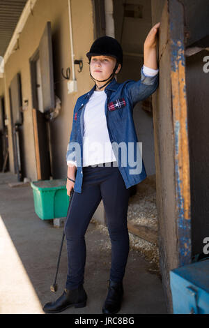 Thoughtful girl standing in the stable Stock Photo