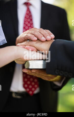 Close-up of couple taking an oath on bible during wedding Stock Photo