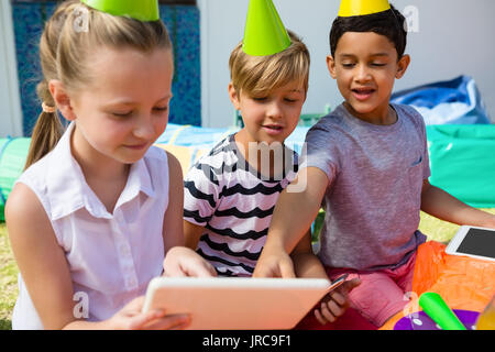 Children using digital tablet during birthday party in yard Stock Photo