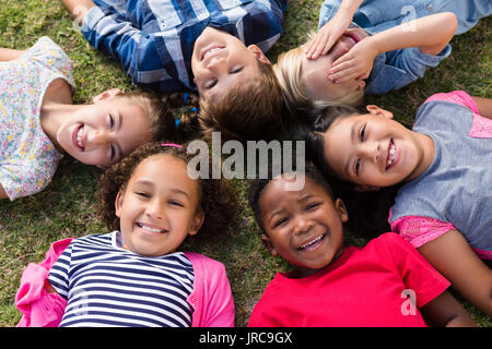 Directly above portrait of children lying on field in yard Stock Photo