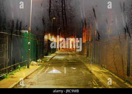 Looking through a misty window with raindrops at a deserted inner city alleyway in the rain Stock Photo