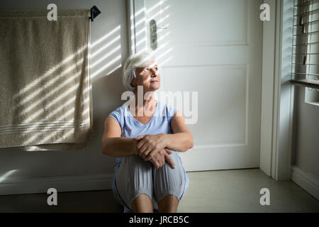 Tense senior woman looking through window in bedroom Stock Photo