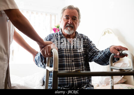 Midsection of female doctor standing by senior man holding walker in nursing home Stock Photo
