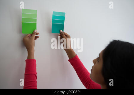 Young woman holding color swatches by wall at home Stock Photo