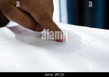 Cropped hand on senior man reading braille book in retirement home Stock Photo