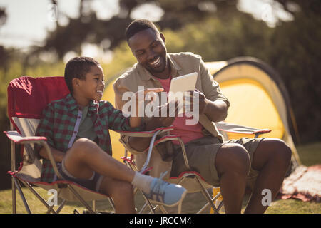 Smiling father and son using digital tablet in park Stock Photo