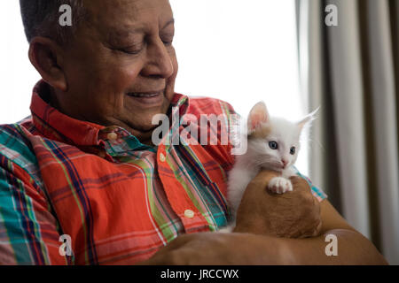 Happy senior man playing with kitten at nursing home Stock Photo