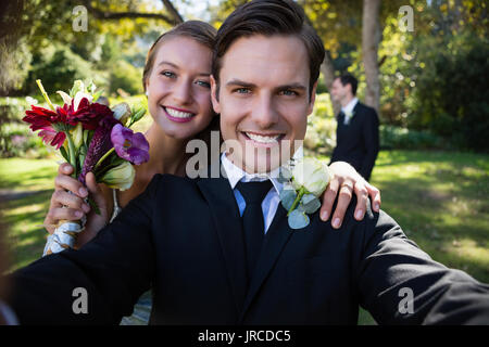 Portrait of happy couple posing in park during wedding Stock Photo