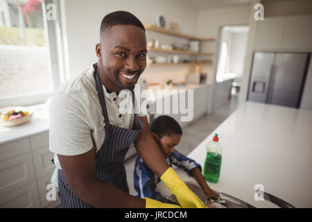 https://l450v.alamy.com/450v/jrcdcm/portrait-of-smiling-father-and-son-cleaning-utensils-in-kitchen-at-jrcdcm.jpg